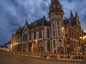 Gothic building at night with illuminated streetlights and a bicycle in the foreground, blue hour