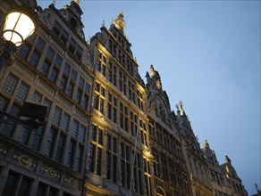 Close-up of a gothic building with evening lighting and street lamp, the historic market square of