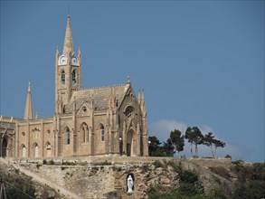 A gothic church with pointed towers and blue skies, majestically built on a rock, the island of