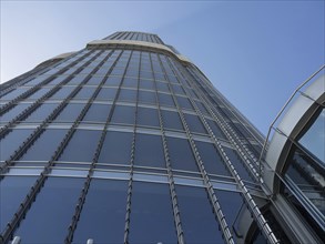 View upwards to a modern skyscraper with glass facade and a clear sky, dubai, arab emirates