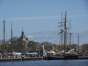 View of a harbour with sailing boats and a church tower in the background on a clear day,