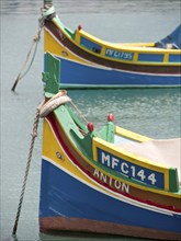 Two brightly painted boats in calm water, close-up of the sides of the boats, colourful boats in a
