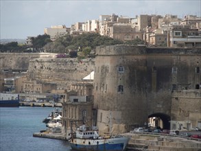 Historic harbour town with old stone walls, boats and buildings along the waterfront, Valetta,