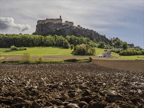 Clods of earth in farmland, Riegersburg Castle in the background, near Riegersburg, Styria,