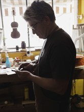 Craftsman focused on work in a sunlit workshop with various tools and instruments