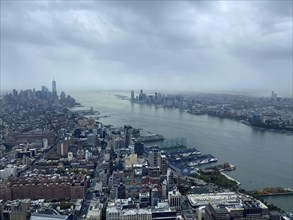 Aerial view of a large city with skyscrapers and a river, cloudy sky and expansive views, the