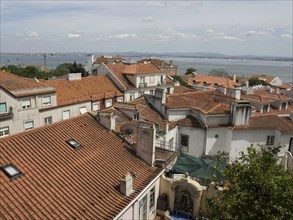 View of a city with red roofs, the sea in the background and a slightly cloudy sky, Lisbon,