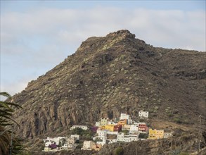 Colourful houses on a hill in the middle of a rocky mountain landscape under a blue sky, tenerife,