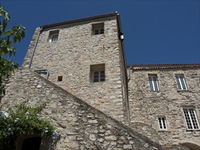 A historic building with stone walls and multiple windows under a clear blue sky, architectural