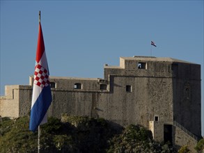 Historic castle with Croatian flag and clear blue sky, the old town of Dubrovnik with historic