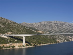 Long, modern bridge spanning a river in a picturesque mountain landscape, the old town of Dubrovnik