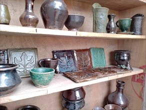 Glazed pottery on display of handcrafted ceramic pottery on wooden shelves