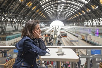Woman Waiting in a Restaurant with View over Milan Railroad Station with Trains in Milan, Lombardy,