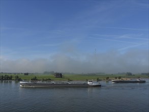 Several ships on a river in a green, natural landscape under a blue sky, ships on the rhine river