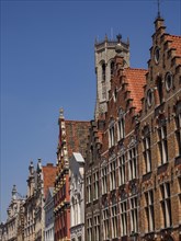 Row of historically decorated gabled houses under a bright blue sky, historic house facades in a