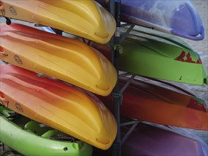 Colourful kayaks are stacked on top of each other and stored on a beach, Baltrum Germany