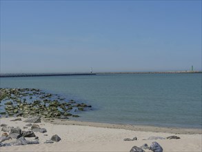 A quiet beach with rocks, a lighthouse and calm sea on a sunny day, lighthouses at a harbour