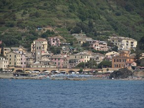 A coastal town with colourful buildings by the water, surrounded by green hills, Bari, Italy,