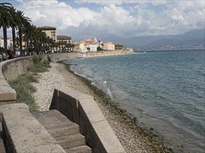 Coastal promenade with a view of the sea and historic buildings in the background, Corsica,