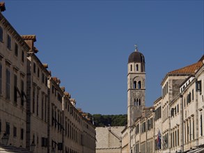 View along a historic street with a bell tower in the background and blue sky, the old town of