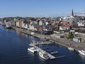 Scandinavian city promenade by the water with boats and colourful buildings, harbour in norway with