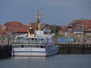 Large ship in the harbour, surrounded by buildings, quietly moored at the jetty, Baltrum Germany