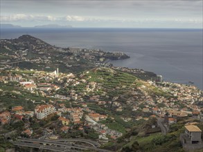 View of a coastal town with green hills in the foreground and the blue sea in the background,