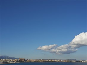 A wide blue sky with scattered clouds and a city view on the horizon over the sea, palma de Majorca