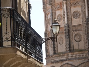 A decorated balcony with a lantern next to a historic building, palermo in sicily with an