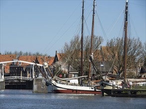 A harbour with sailing boats and buildings on the water under a blue sky, Enkhuizen, Nirderlande