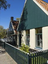 Traditional green houses with white fences along a street in a sunny village, Enkhuizen,