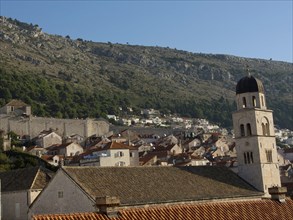 City view with historic roofs and church tower in front of a mountain landscape, the old town of