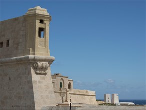 Stone tower and architectural structures on a coastline overlooking the blue sea, Valetta, Malta,