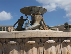 Detailed sculptures in a fountain under a blue sky with clouds, Valetta, Malta, Europe