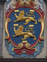 Close-up of a coat of arms with golden lions and colourful decorations, historic houses in Hoorn