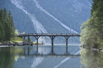Landscape of a bridge over a small part of a clear lake (Plansee) in autumn in Tirol
