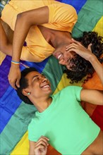 Top view vertical photo of a multi-ethnic male gay couple lying together over a LGBT rainbow flag