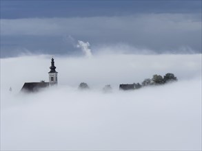 Church tower rises out of the morning mist, Frauenberg pilgrimage church, near Leibnitz, Styria,