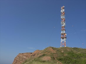 Transmission mast on a green hill in front of a clear blue sky, Heligoland, Germany, Europe