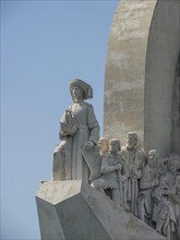 A stone monument with several human statues and a leading figure under a clear blue sky, Lisbon,