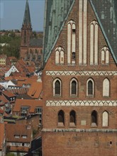Partial view of a gothic brick church tower and surrounding medieval town, red brick church in