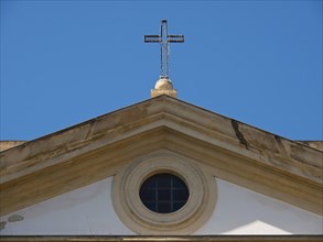 Church facade with a cross on the roof under a clear blue sky, palermo in sicily with an impressive