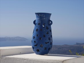 Blue vase with star and moon motifs on a white terrace with sea and mountain views in the