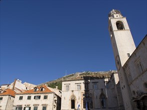 Clock tower and historic buildings in an old town under a clear blue sky, the old town of Dubrovnik