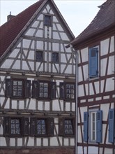 Historic half-timbered house with blue shutters and rustic architectural details, historic