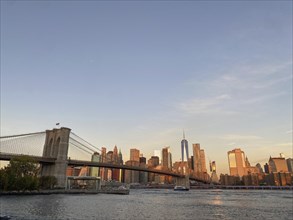 Panoramic view of the Manhattan skyline with the Brooklyn Bridge at sunset, historic bridge in the
