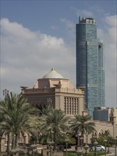 A modern skyscraper with an older building in front of it and a clear sky in the background, dubai,