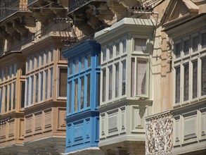 A series of colourful, ornate balconies and windows of buildings in the city, the island of Gozo