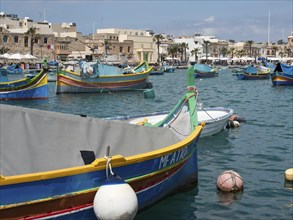 Colourful fishing boats anchored in the harbour of a coastal town, with buildings in the
