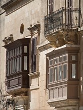Two balconies made of wood and iron on a historic facade, the town of mdina on the island of malta